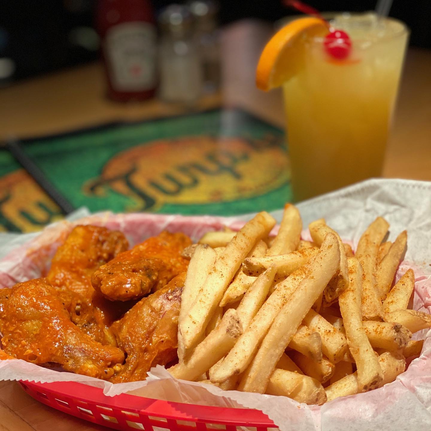 A basket of wings and fries with a cocktail