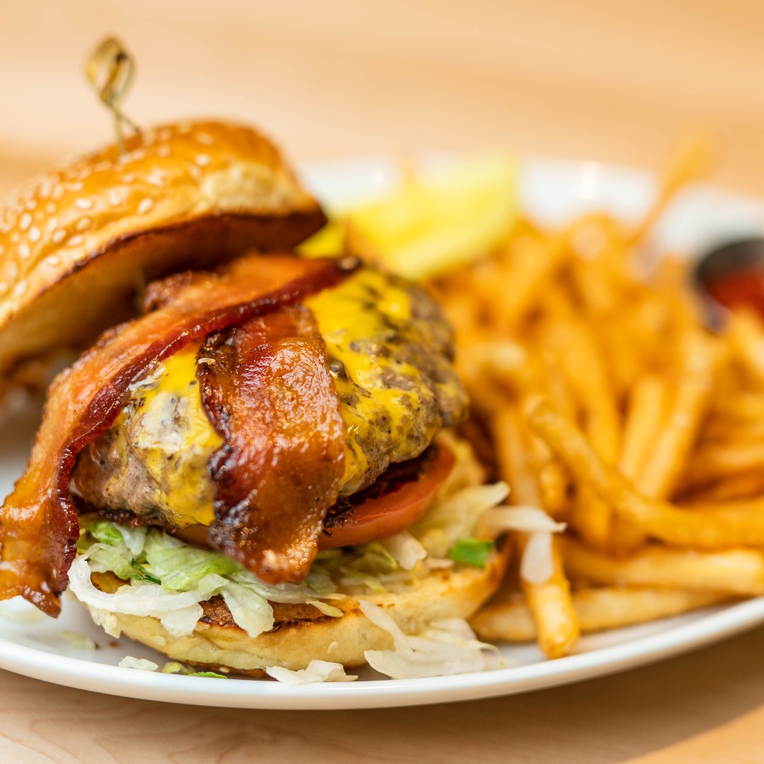 A smash burger with bacon and a side of fries