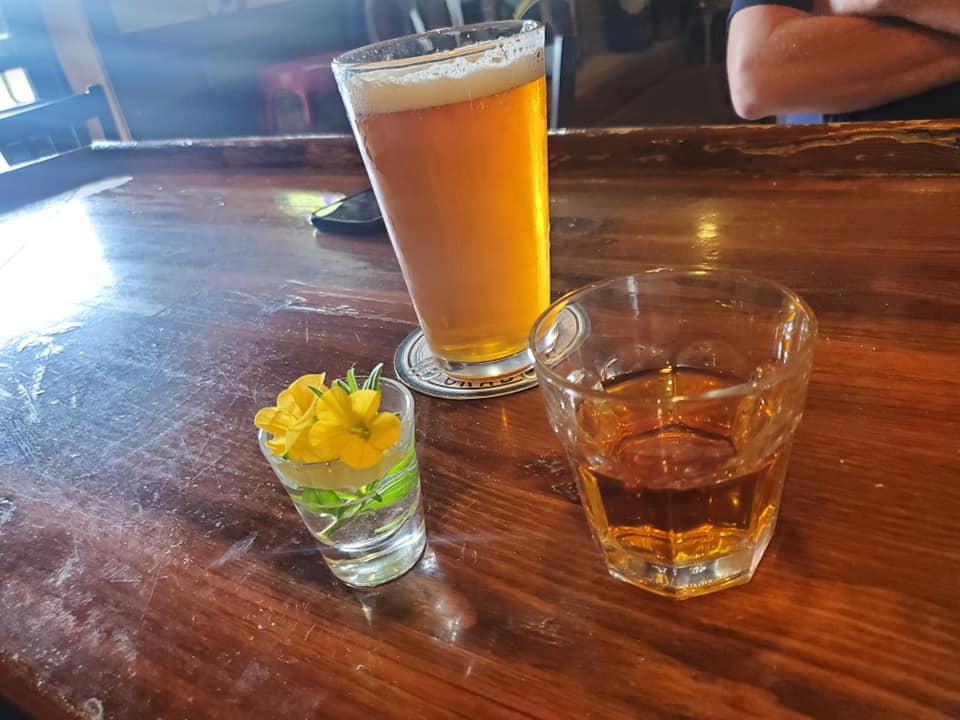 a glass of beer and a small glass of liquid on a table