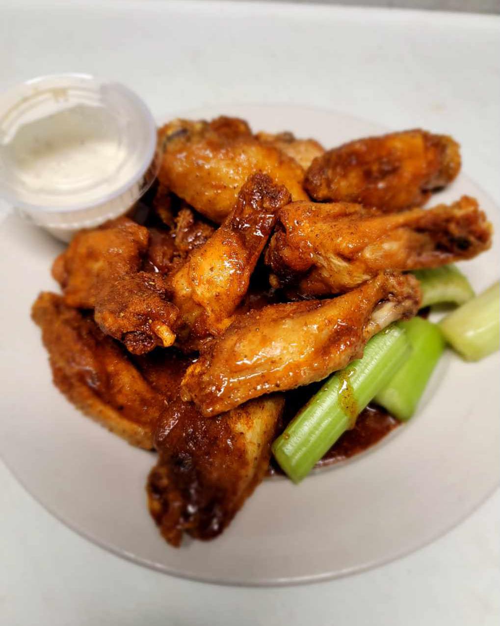 chicken wings, celery, and dip on a plate