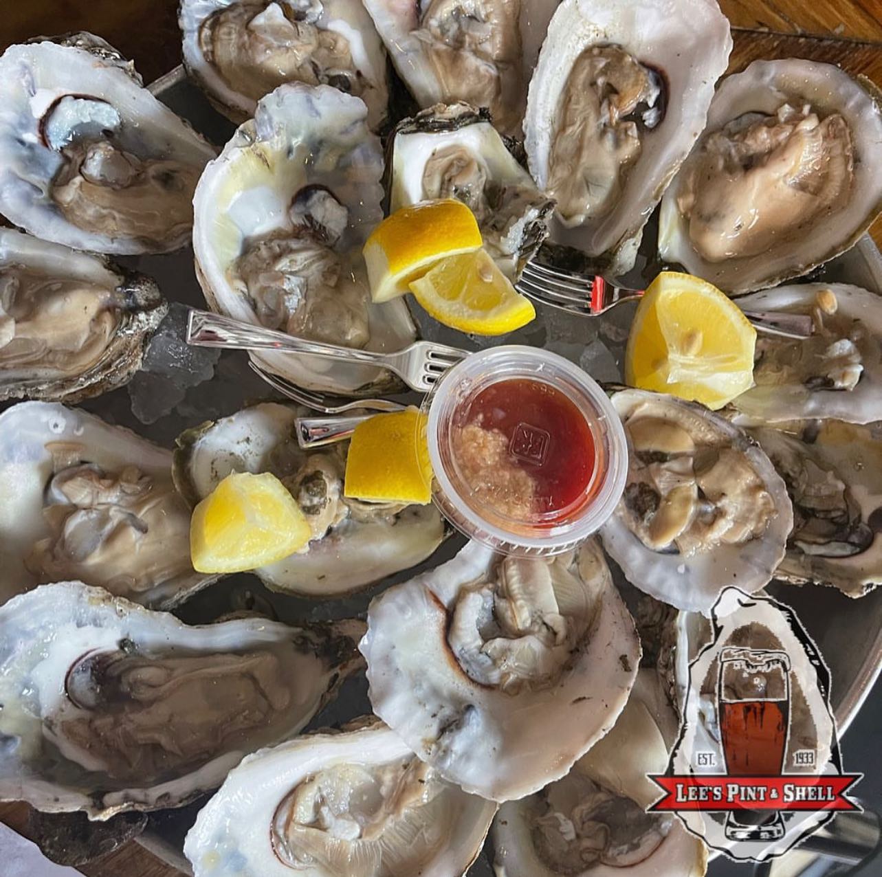 a plate of oysters with lemon wedges and sauce