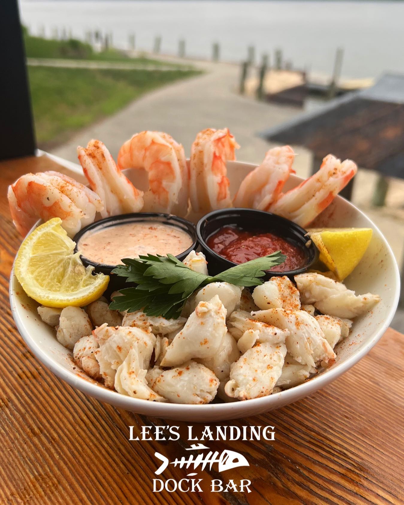 a bowl of jumbo lump crab and jumbo shrimp with cocktail and remoulade sauces and lemon wedges