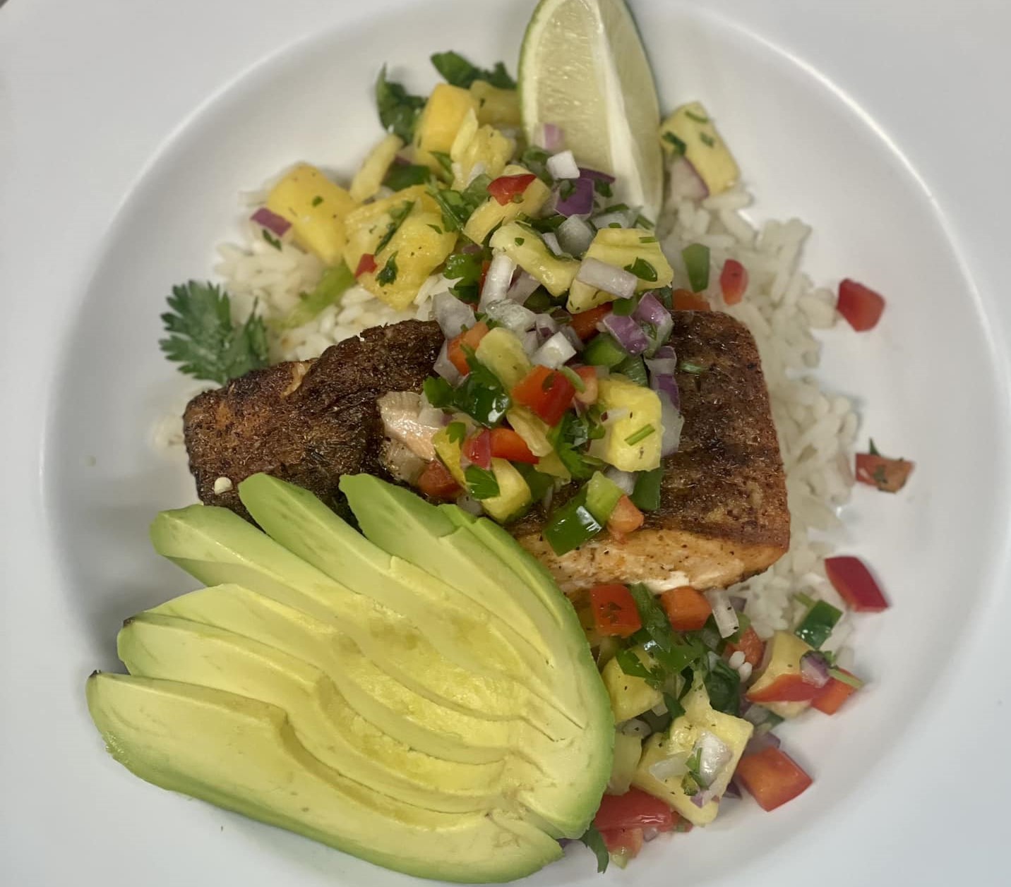 a plate of teriyaki salmon with a sliced avocado and rice