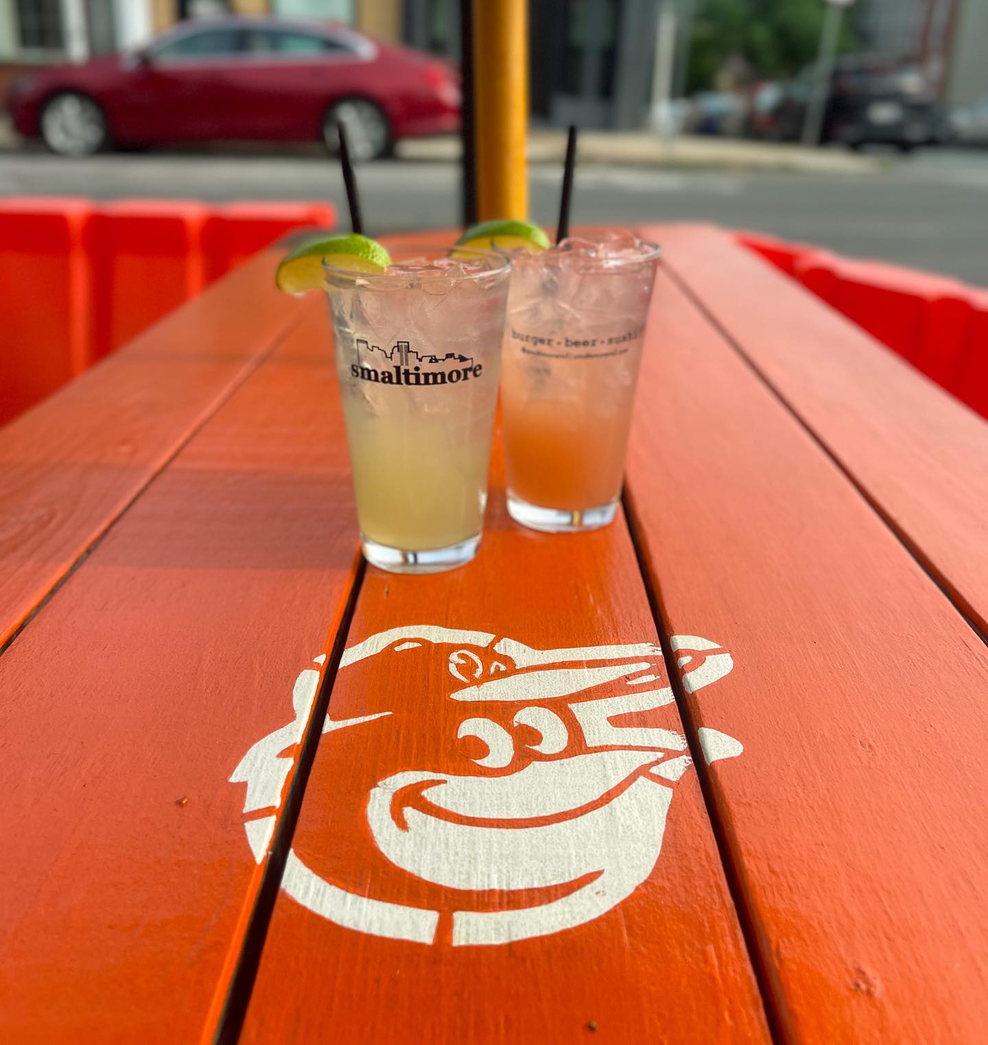 two mixed drinks on an orioles picnic table outside