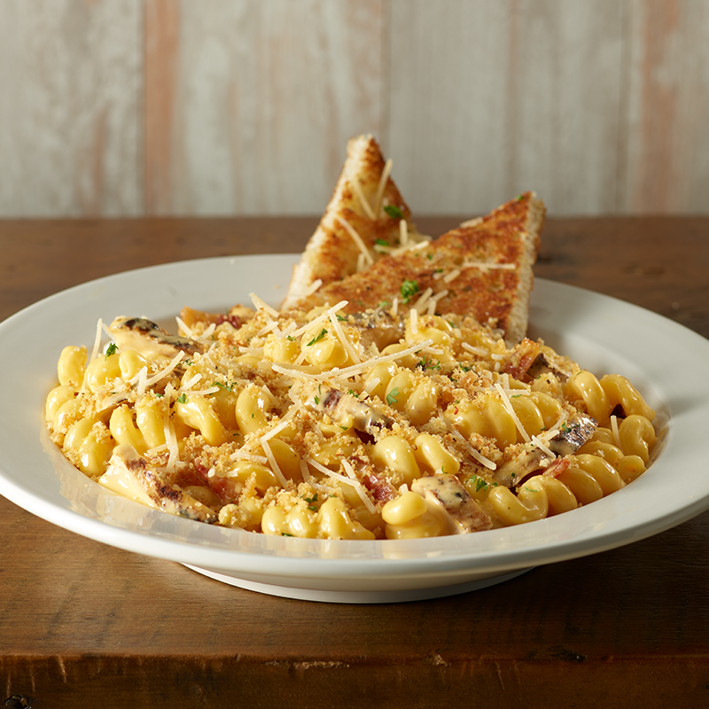 a plate of mac and cheese with bread crumbs and grated cheese