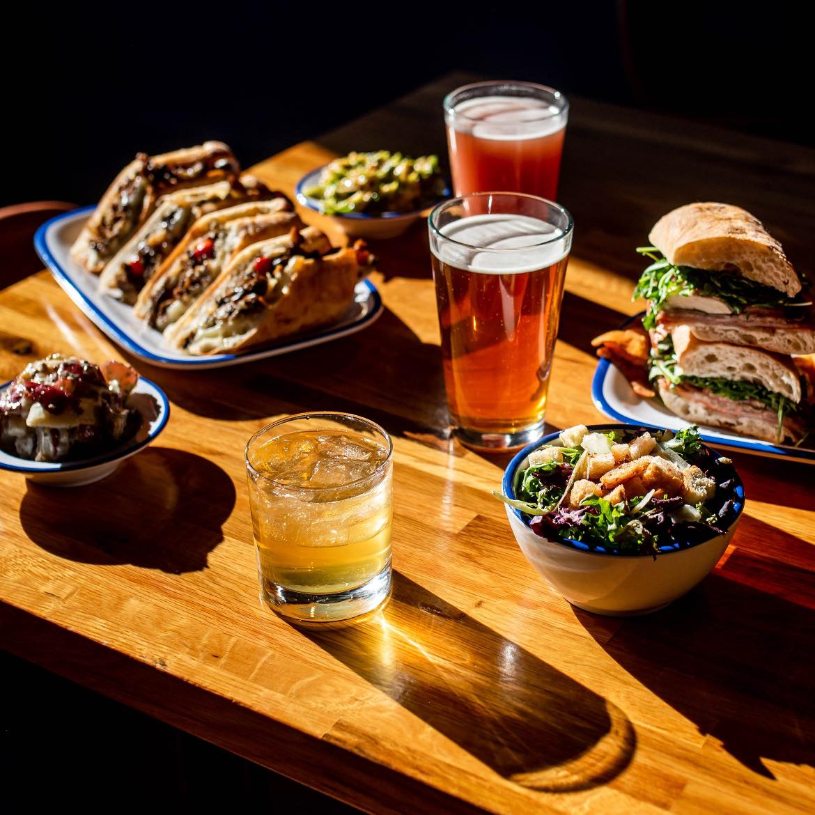 several plates of food and three drinks on a table