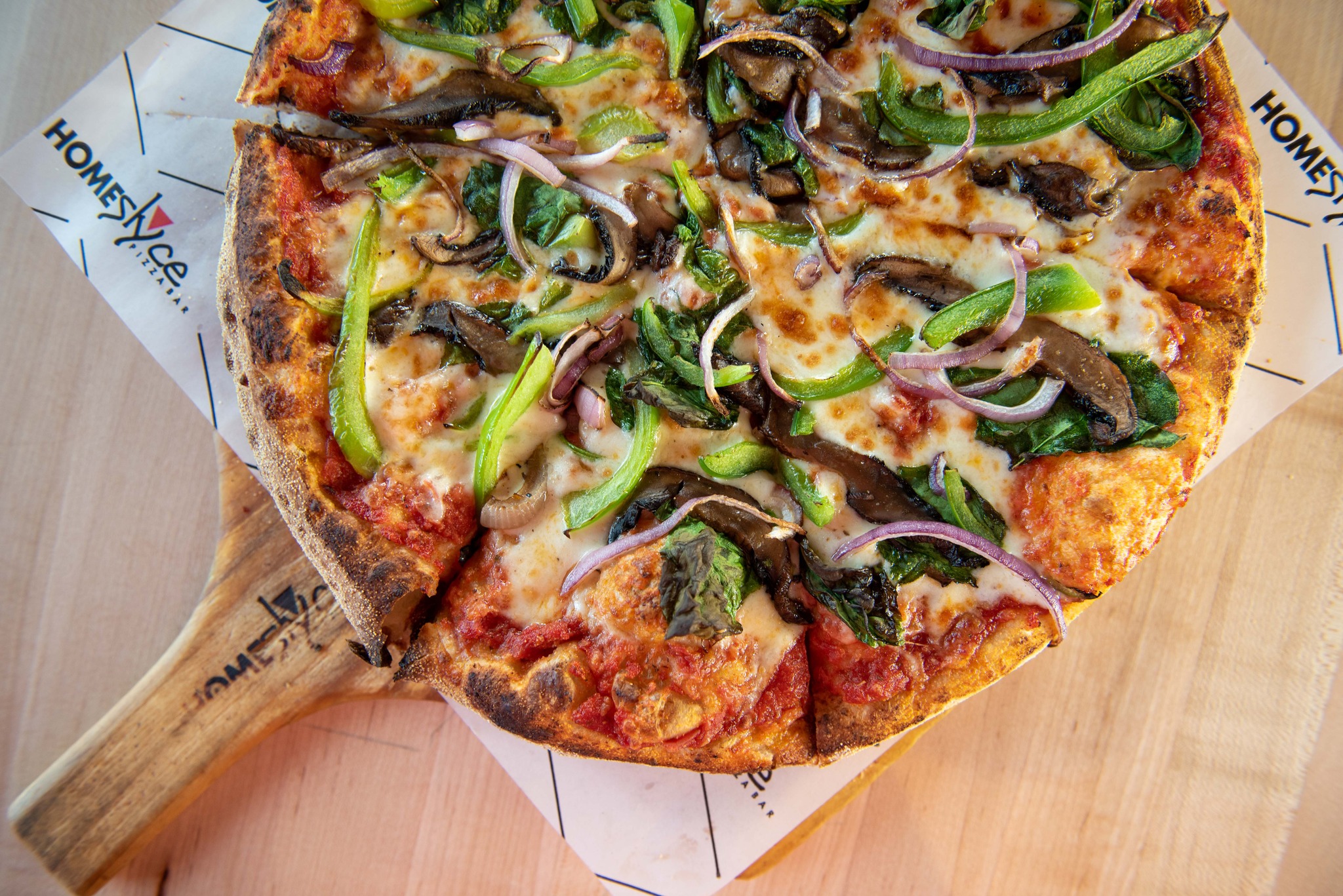 a bell pepper, onion, and mushroom pizza on a peel