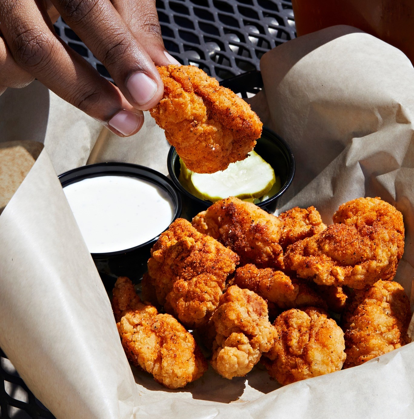 a basket of wings with pickles and dip