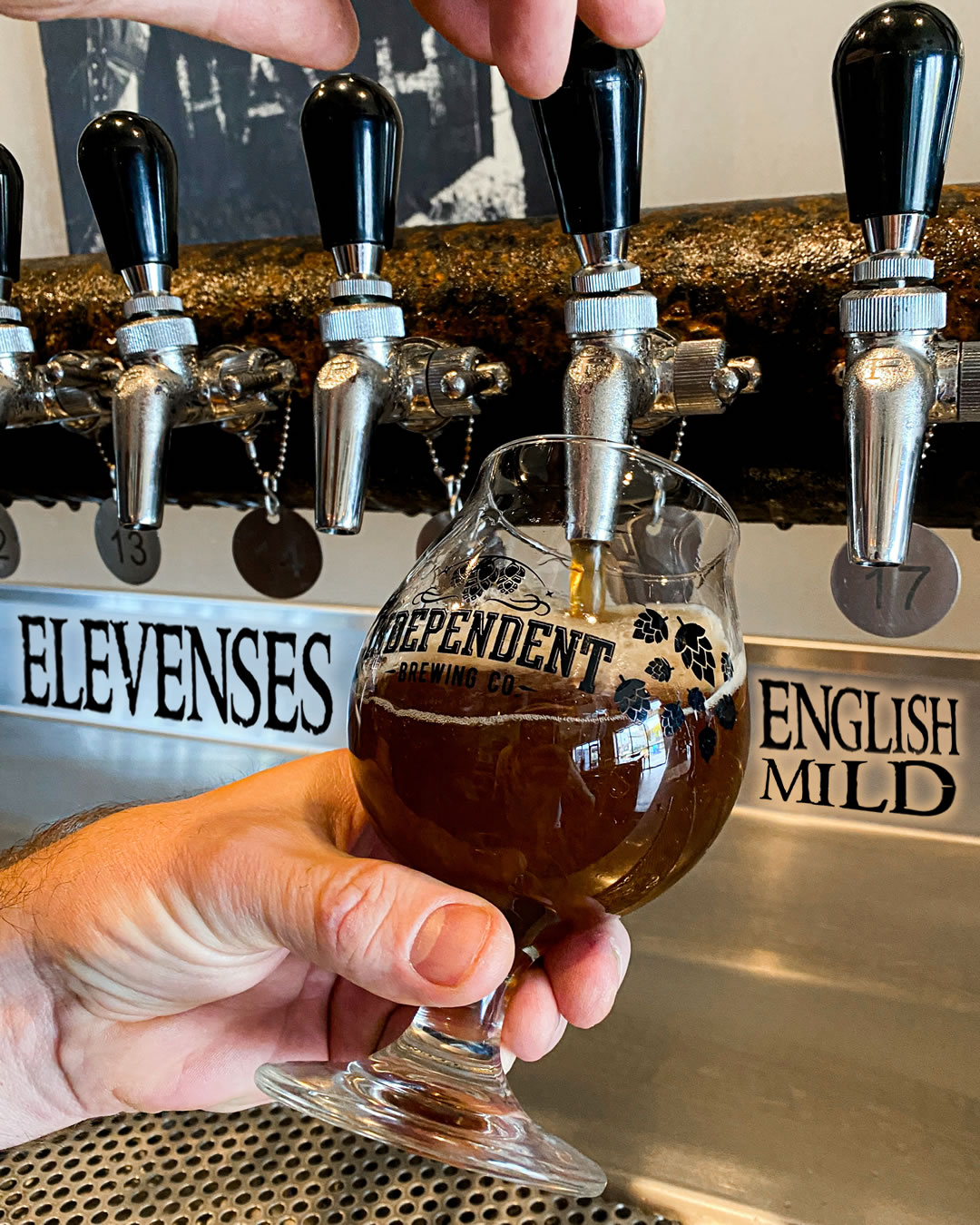 a bartender pouring a glass of beer from the taps