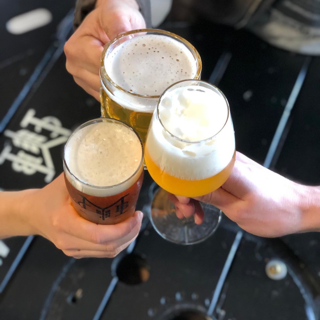 three people cheersing their glasses of beer