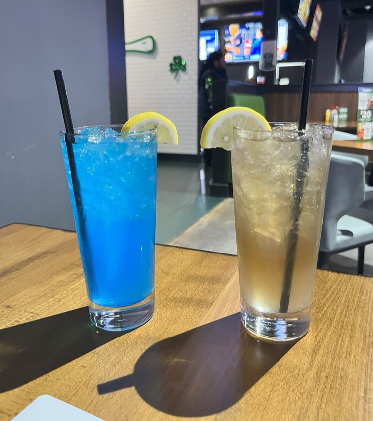 two drinks with lemon wedges, one blue and one yellow