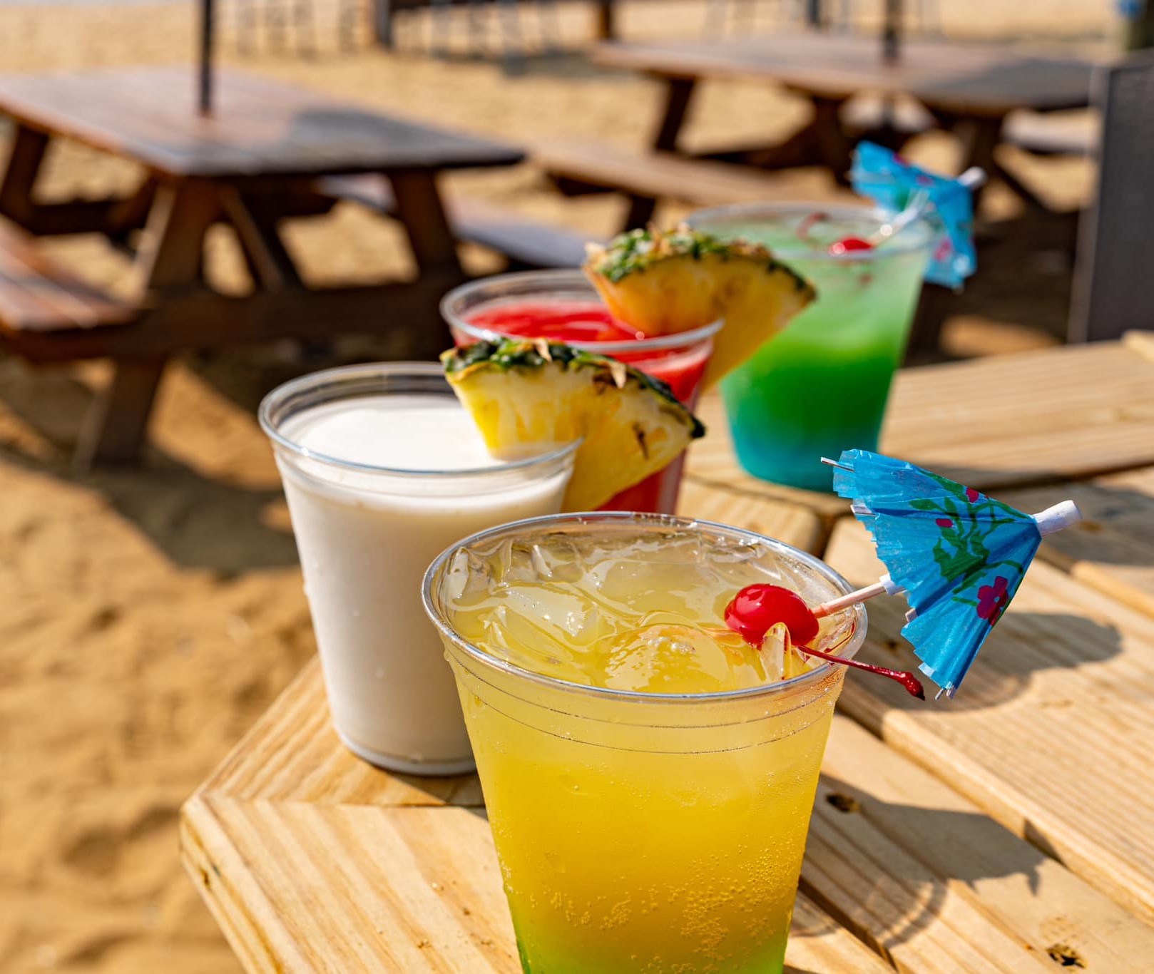 four different color cocktails on a table outside