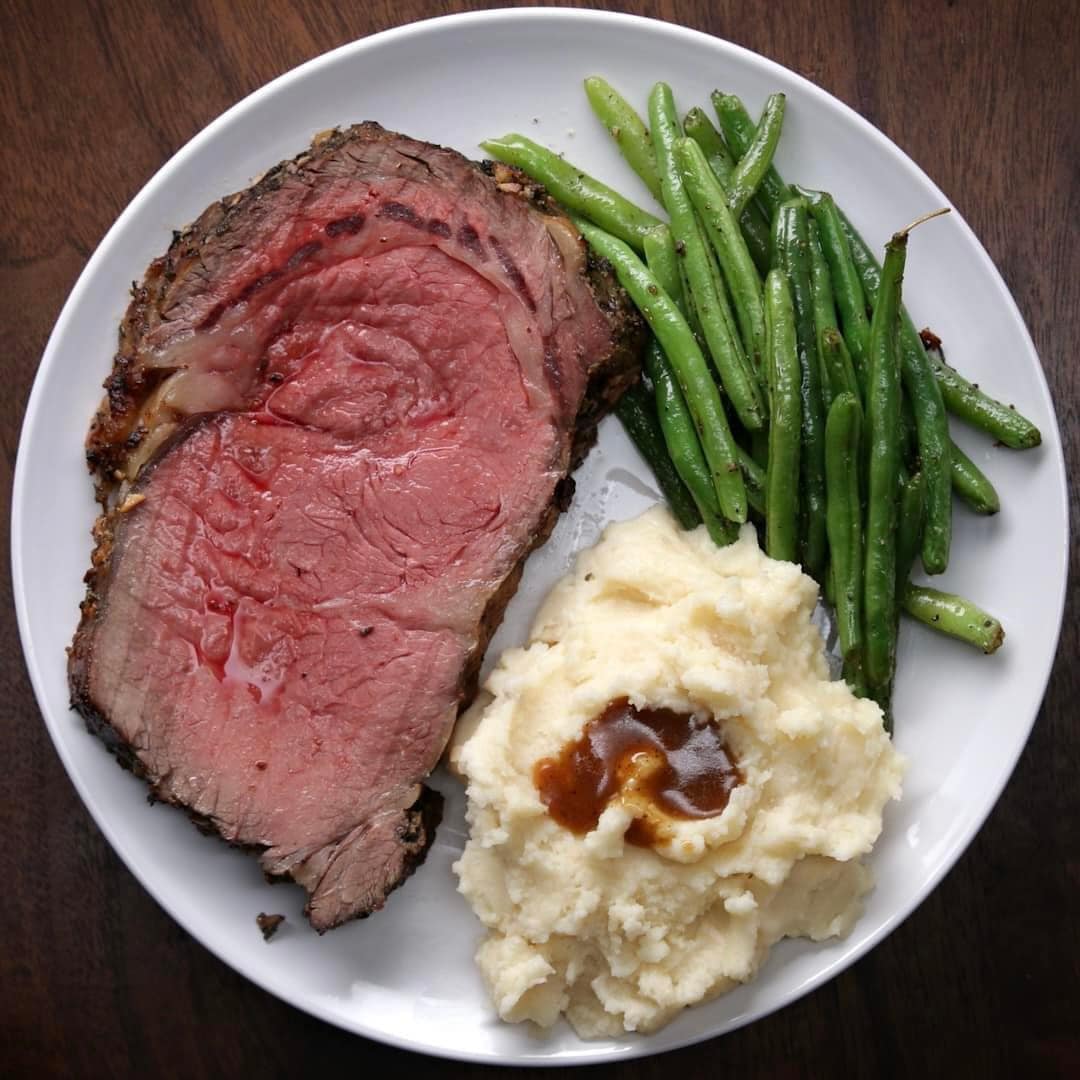 a prime rib with mashed potatoes and green beans