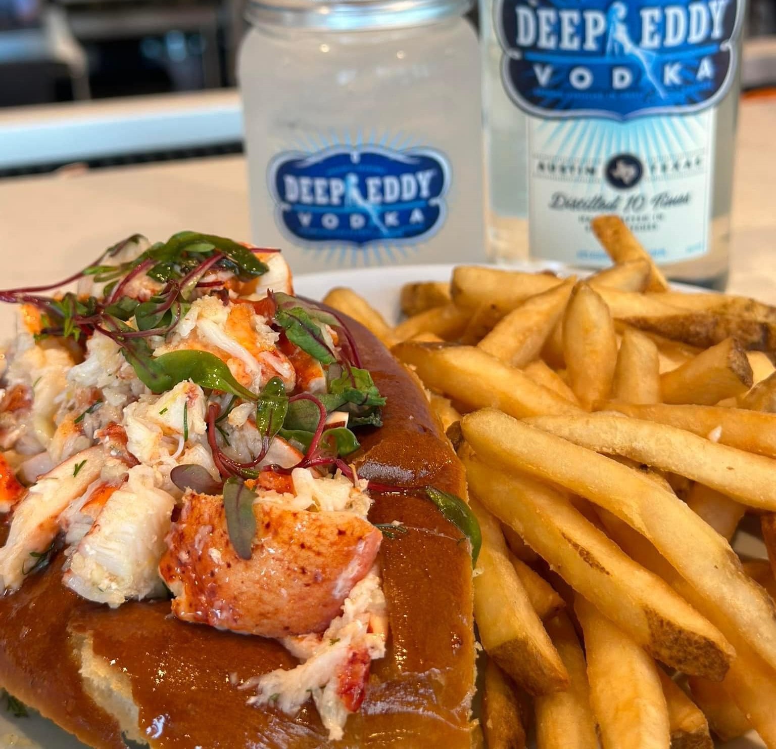 a lobster roll with fries and a drink