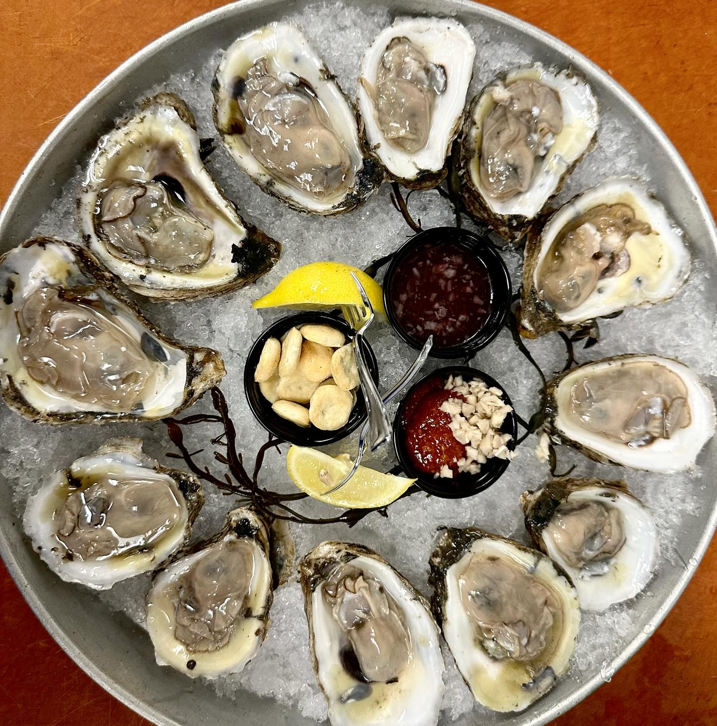 a platter of fresh oysters with lemon wedges and dips