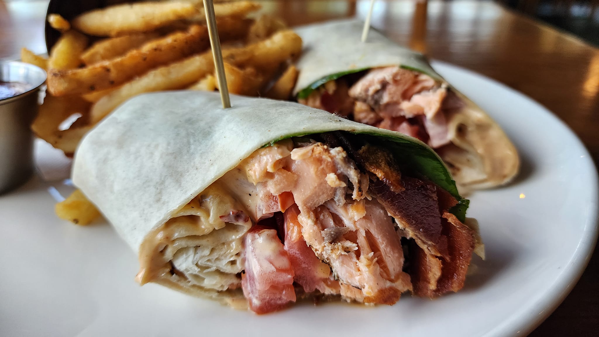 a salmon BLT wrap on a plate with fries