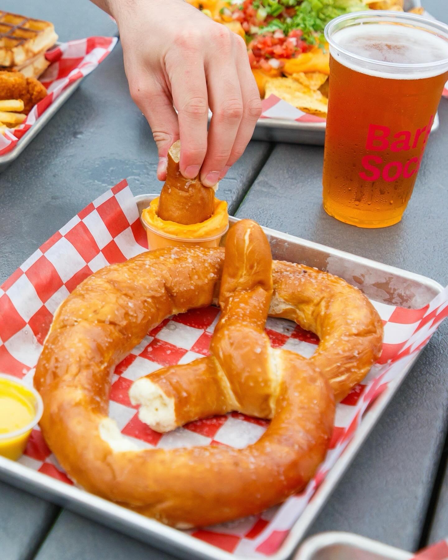 a soft pretzel with cheese dip and a beer