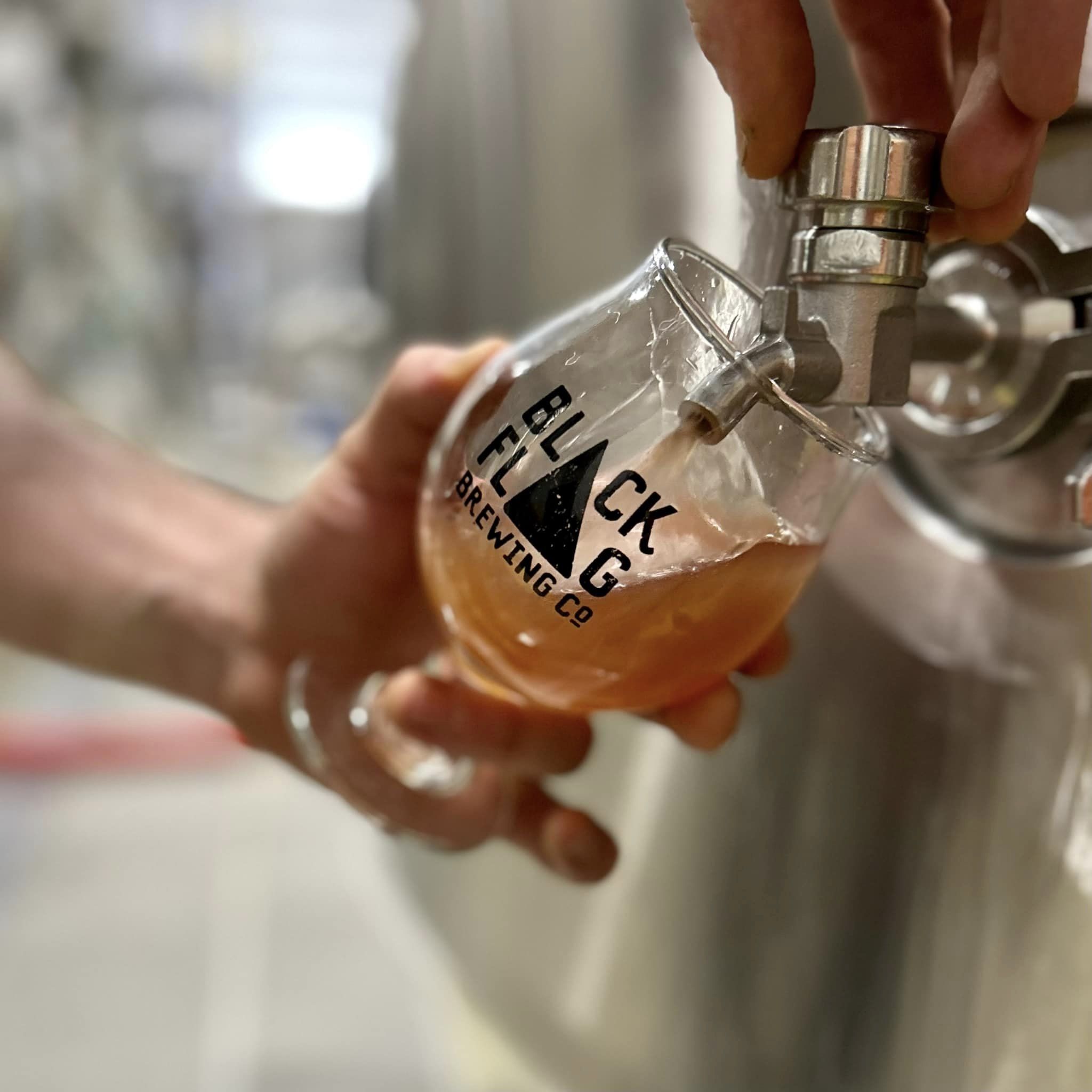 a person filling a glass at a beer tap