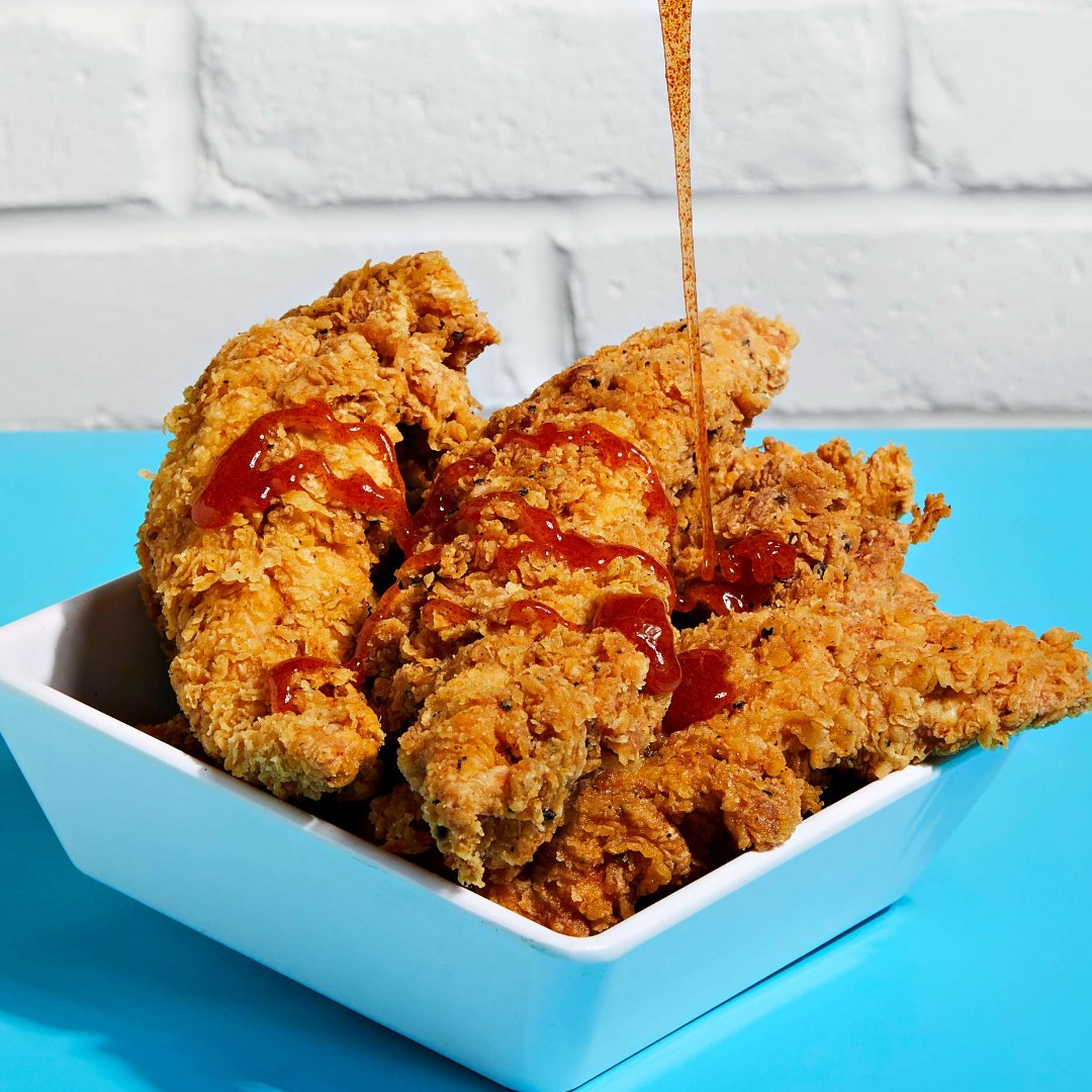 a plate of fried chicken with hot honey drizzle