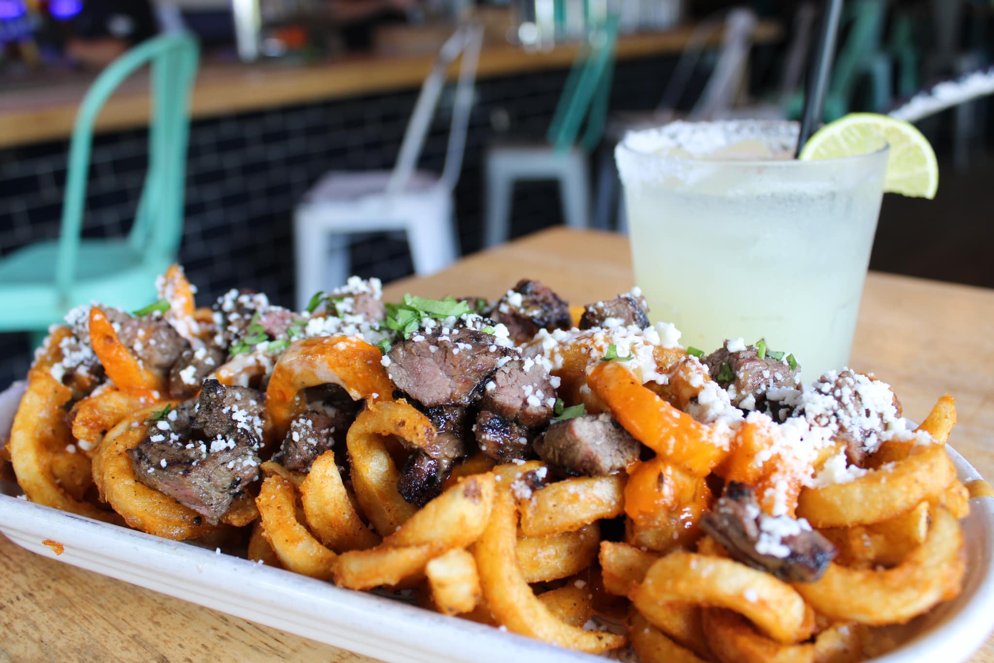 a plate of Carne Asada Fries and a margarita with a lime wedge