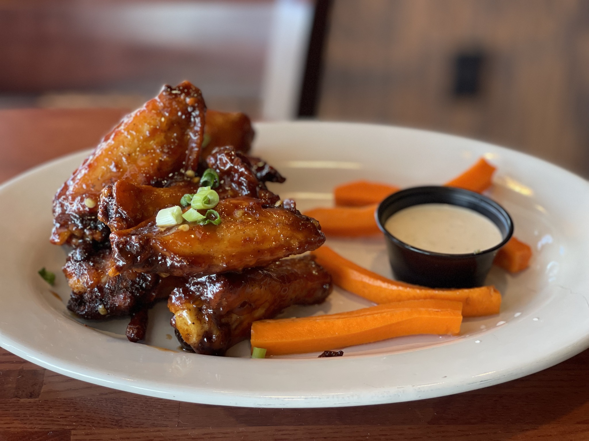 a plate of Sizzling Szechuan Wings with carrot sticks and dip