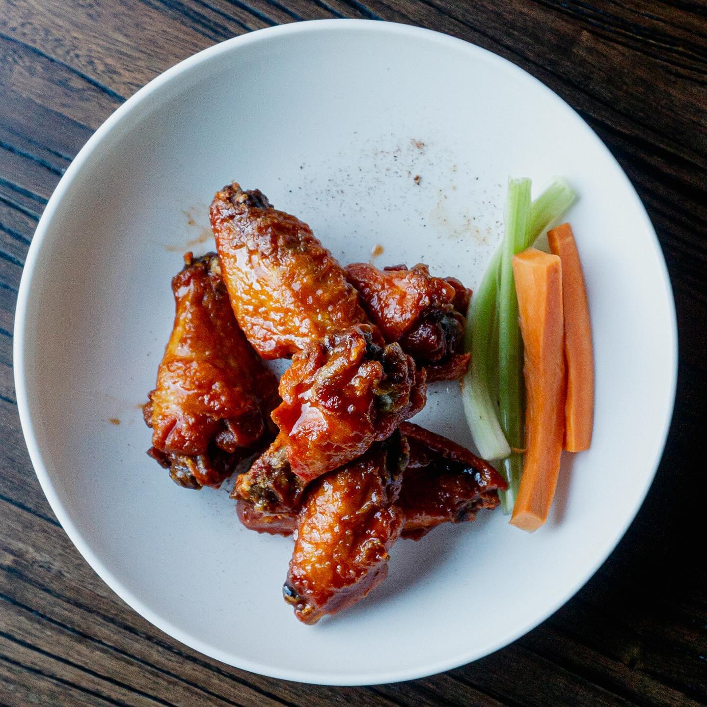 a plate of wings with celery and carrots