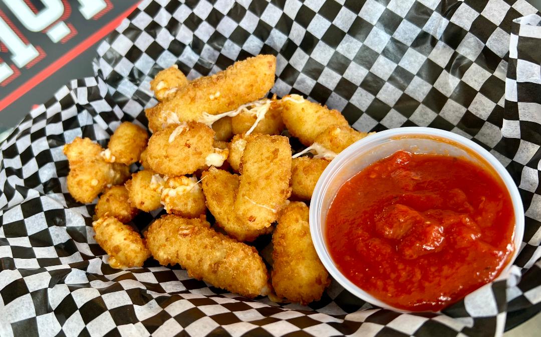 a basket of fried cheese curds with sauce