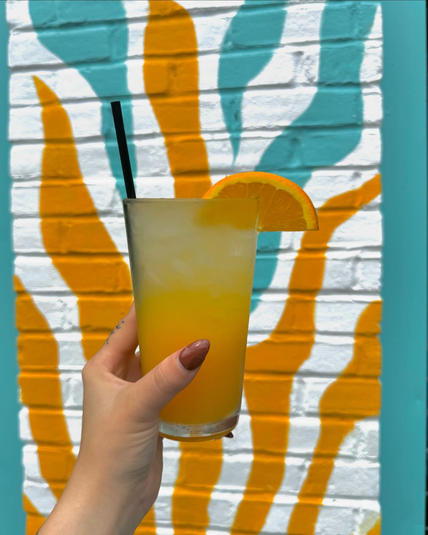 a mimosa with an orange wedge and a straw