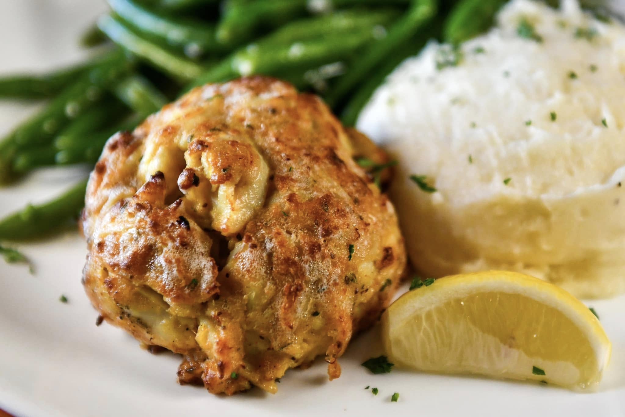 a crab cake with mashed potatoes and green beans