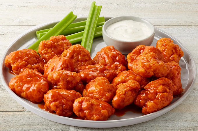 a plate of wings with celery and dip