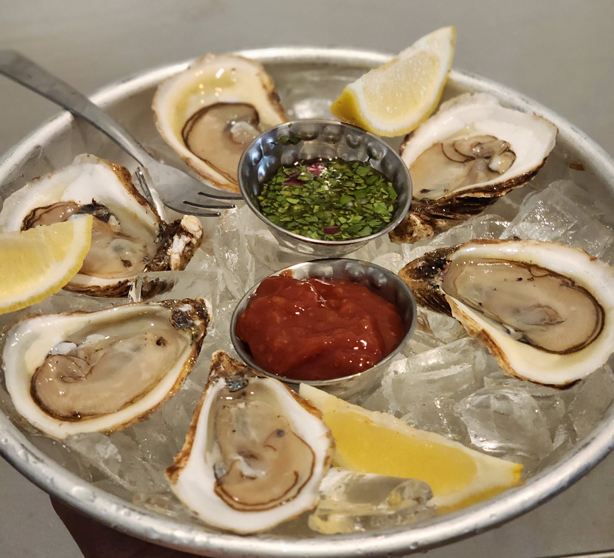 oysters on ice with sauces and lemon wedges
