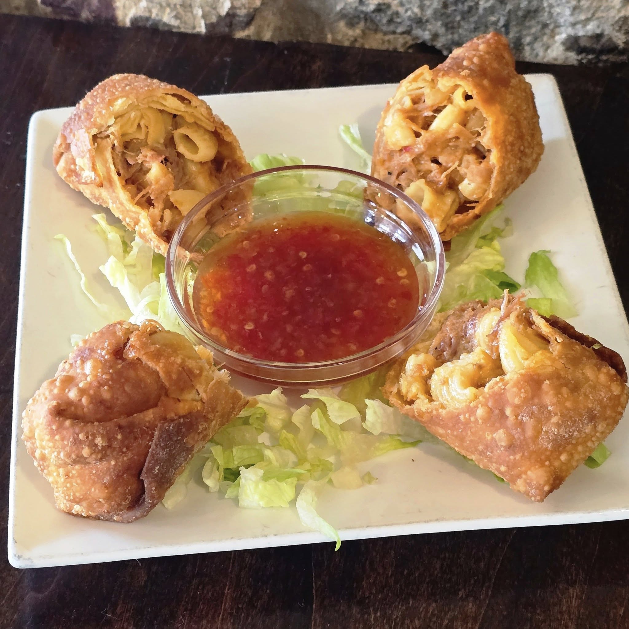 a plate of Pulled Pork Mac N Cheese Eggrolls with dip