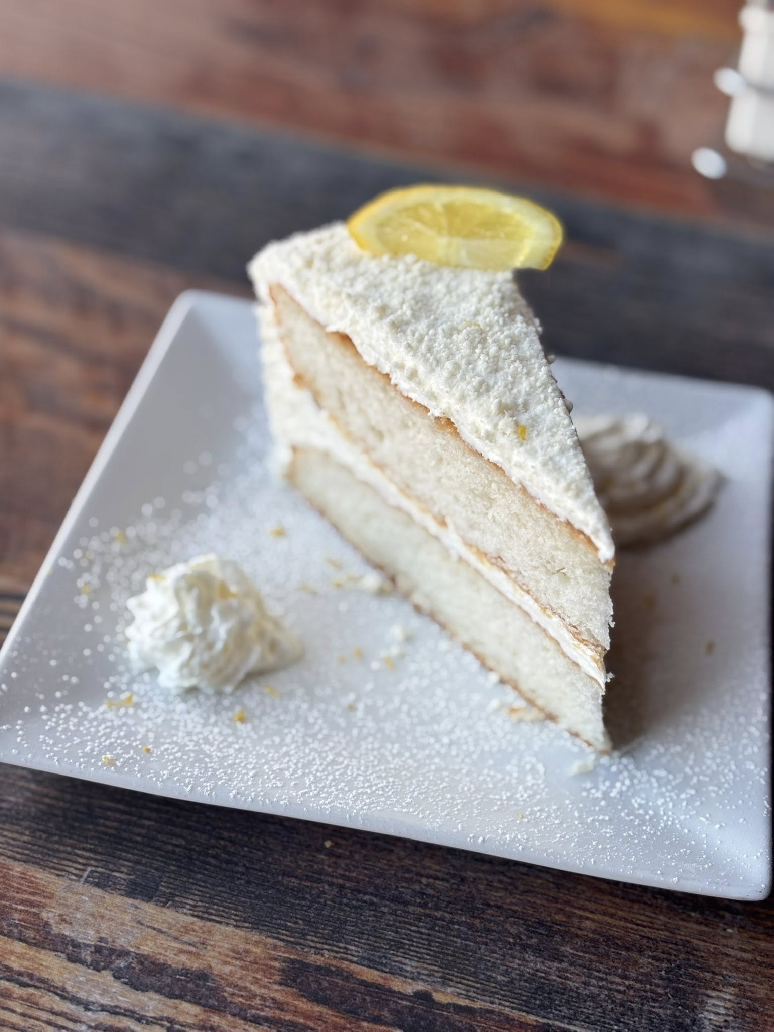a slice of cake with a lemon wheel and powdered sugar