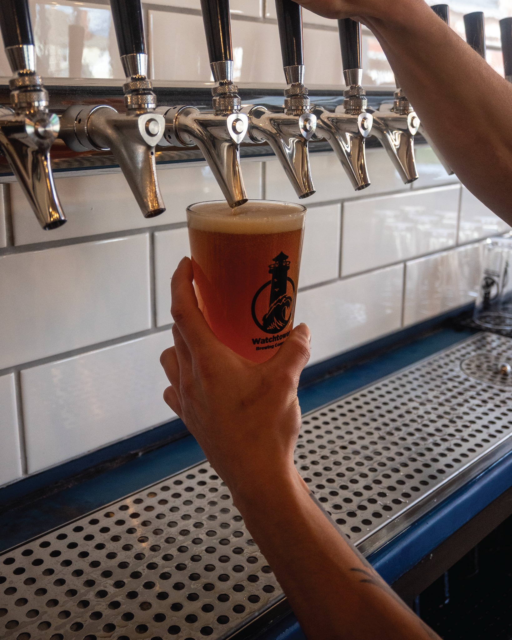 a person pouring a glass of beer from the tap