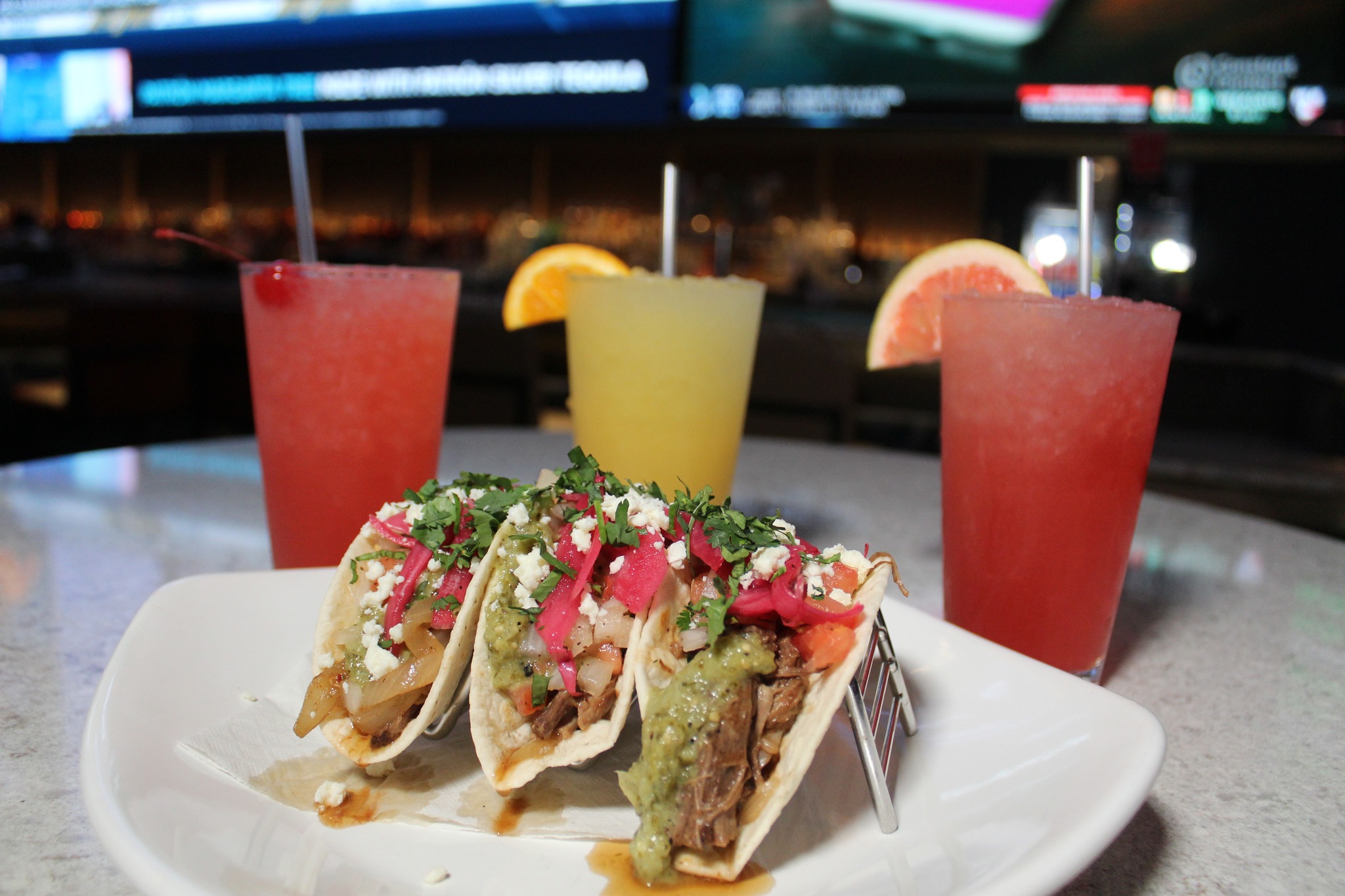 a plate of three tacos with three cocktails