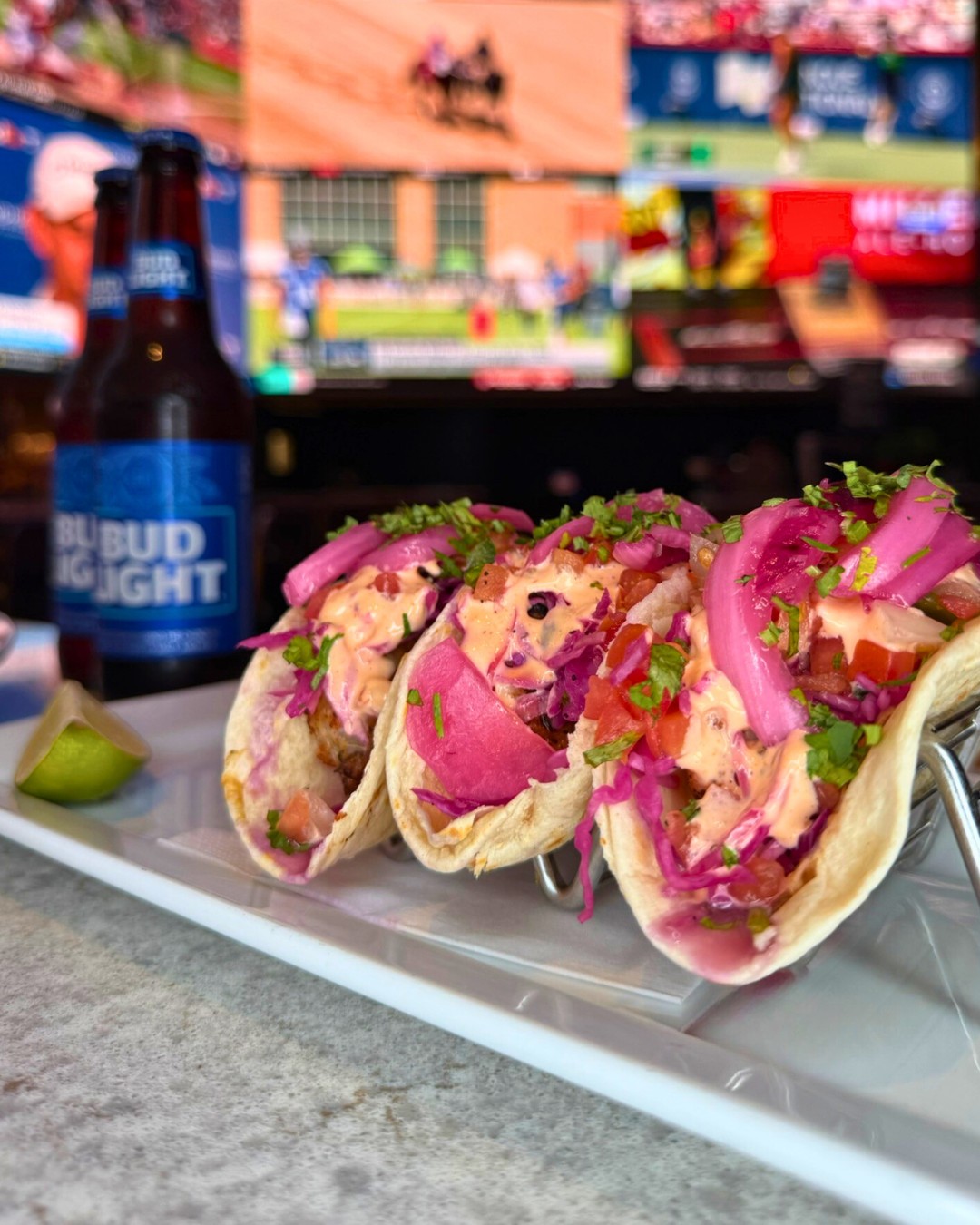 a plate of three tacos with two bottle of beers