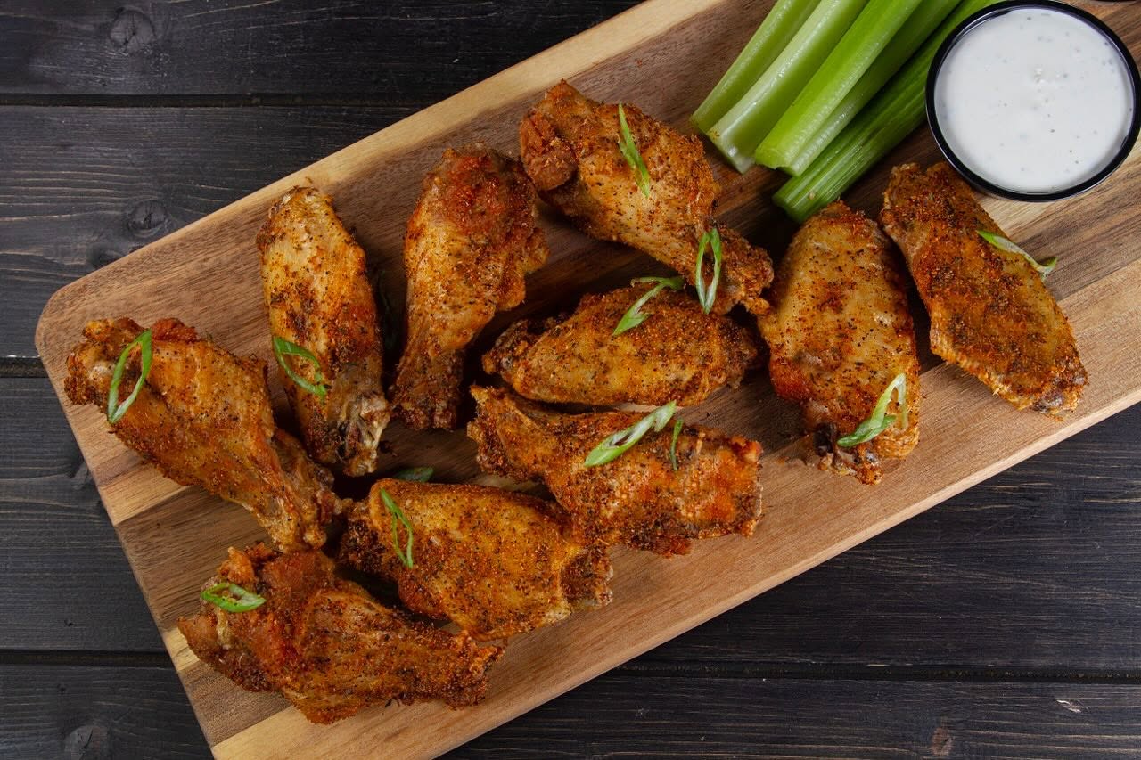 a platter of wings with celery and dip